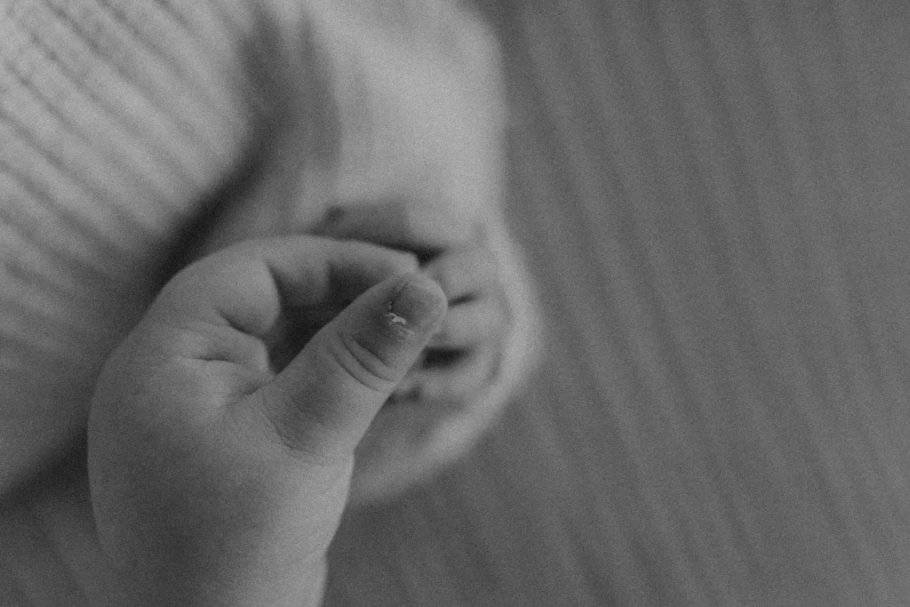 Close-up of newborn’s tiny hand with peeling skin in black and white