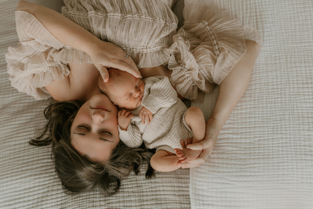 Mother lying on bed with sleeping newborn resting on her chest