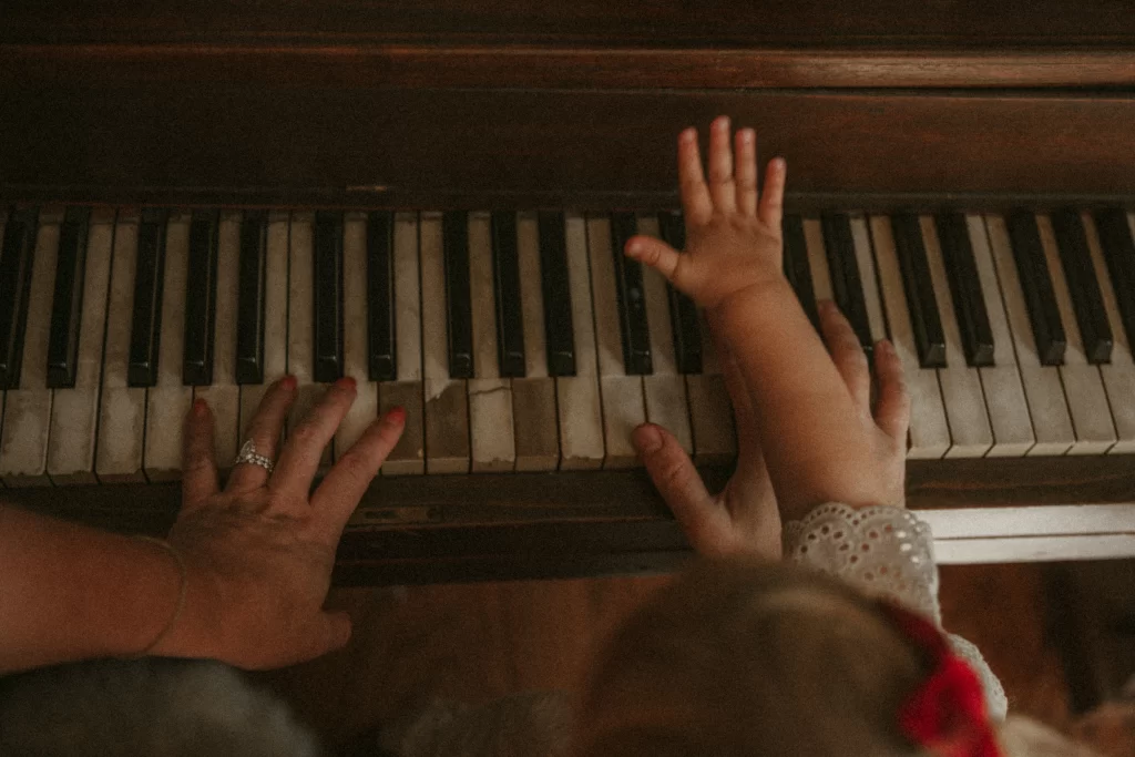 Toddler and parent hands playing piano keys together during cozy Christmas session