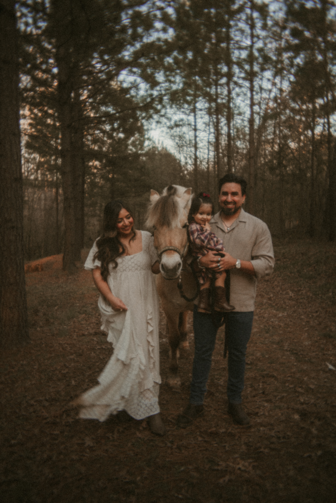 Family standing together with their toddler and horse during an outdoor woodland family photo session